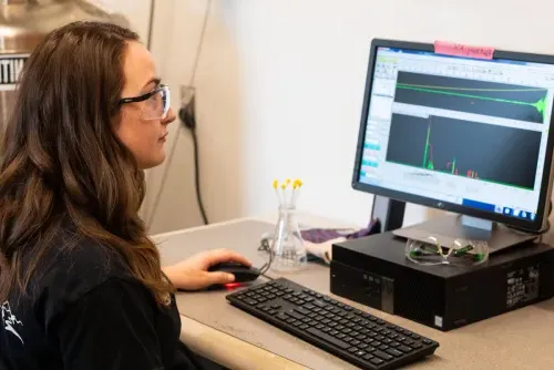 A student sits in front of a computer monitor that displays graphical data from a chemistry experiment