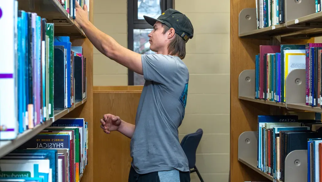 A student peruses the books in the library