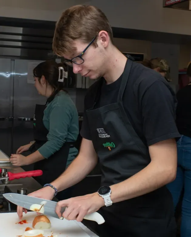 Nutrition students chop onions in the U N E class kitchen