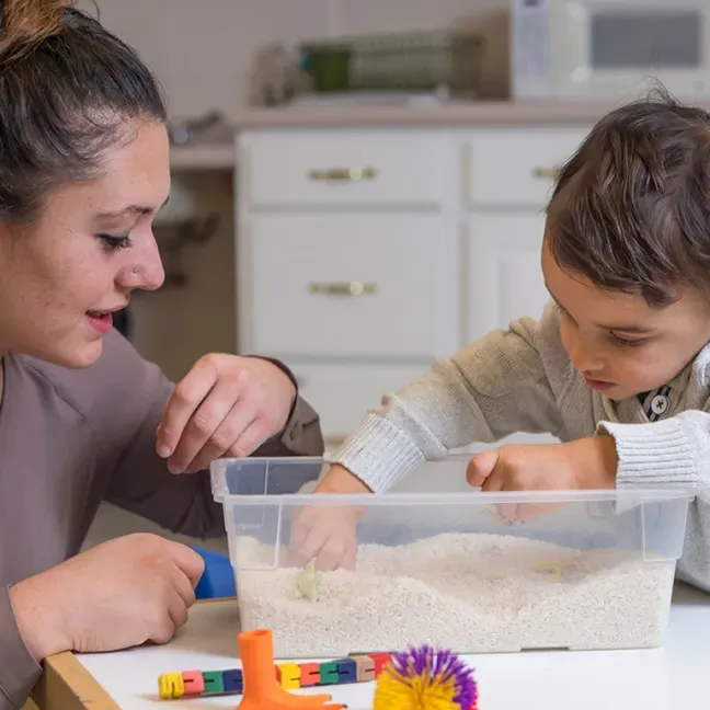 a u n e student works with a child using a sensory table