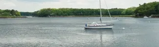 A boat sits in the center of a lake surrounded by a forest